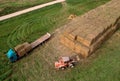 Farmer unloading round bales of straw from Hay Trailer with a front end loader. Store hay at farm. Hay rolls as Forage feed for
