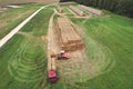 Farmer unloading round bales of straw from Hay Trailer with a front end loader. Store hay at farm. Hay rolls as Forage feed for