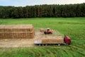 Farmer unloading round bales of straw from Hay Trailer with a front end loader. Store hay at farm. Hay rolls as Forage feed for