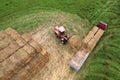 Farmer unloading round bales of straw from Hay Trailer with a front end loader. Store hay at farm. Hay rolls as Forage feed for