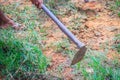 Farmer is using hoe to mow grass i the field. Mowing the grass in the field with shovel. Hoe with green pruning grasses.