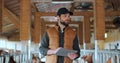 Farmer using tablet computer in modern dairy farm facility cowshed. Agribusiness owner checking data hold tabletPC in Royalty Free Stock Photo