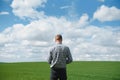 Farmer walking through a green wheat field on windy spring day and examining cereal crops Royalty Free Stock Photo