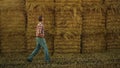 Farmer walking hay stack at agricultural farmland. Worker inspecting rolls pile Royalty Free Stock Photo