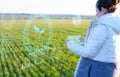 Farmer woman analyzes plants on the field using artificial intelligence. The received data is displayed on a virtual screen availa