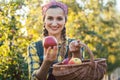 Farmer woman in fruit orchard holding apple in her hands offering