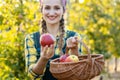 Farmer woman in fruit orchard holding apple in her hands offering