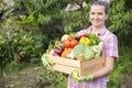 Farmer woman in gloves holding wooden box full of fresh raw vegetables. Basket with vegetable in the hands Royalty Free Stock Photo