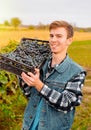 Farmer worker with a smile on his face holding on his shoulder basket of blue ripe grapes posing over the vineyard Royalty Free Stock Photo