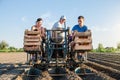 Farmer workers on a tractor plant potato seeds. Automation of process of planting potatoes seeds. High efficiency and speed.