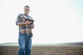 Farmer works in field in spring with tablet. An elderly farmer looks at tablet and green shoots. A smart, agronomist