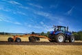 Farmer Works With New Holland Tractor and Leveller