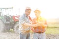 Farmers with digital tablet discussing at farm with yellow lens flare in background