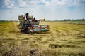 Farmers driving Harvester car during harvesting rice season at rice field farm in Thailand with clear sky and golden rice Royalty Free Stock Photo