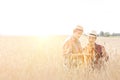 Farmers examining wheat crops at farm against sky