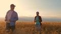 Farmers male and female working with a tablet in wheat field, in the sunset light. businessmen studies income in