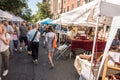 Farmers Market on a bright sunny day showing adults, children, dogs and vendors.