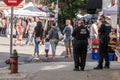 Farmers Market on a bright sunny day showing adults, children, dogs and vendors.