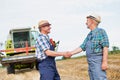 Farmers shaking hands against harvester in field Royalty Free Stock Photo
