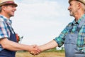 Farmers shaking hands against harvester in field