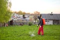 Farmers spraying pesticide on lawn field wearing protective clothing. Insecticide sprayer with a proper protection. Treatment of