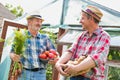 Farmers talking while carrying newly harvest carrots, tomatoes and potatoes at farm