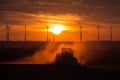 Farmers working with a tractor on the field at sunset with wind turbines in the background Royalty Free Stock Photo