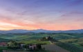 Farmhouse, green hills,cypress trees in Tuscany at sunset