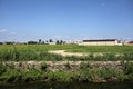 Farmhouse in the middle of a field in summer seen from behind a stream of water in the italian countryside