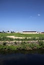 Farmhouse in the middle of a field in summer seen from behind a stream of water in the italian countryside