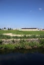 Farmhouse in the middle of a field in summer seen from behind a stream of water in the italian countryside