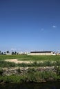 Farmhouse in the middle of a field in summer seen from behind a stream of water in the italian countryside