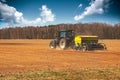 Farming - farmer with tractor on the field seeding sowing crops