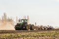 Farming tractor John Deere is working in the field at daylight. Soil cultivation.