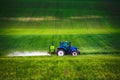 Farming tractor plowing and spraying on green wheat field Royalty Free Stock Photo