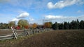 Farmland with a wooden fence under a cloudy sky with the sun shinning through Royalty Free Stock Photo