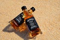 Faro, Portugal - 12/10/2018: Two little bottles Jack Daniels whiskey lie on the sand. Alcohol top view from above