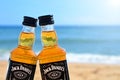 Faro, Portugal - 12/10/2018: Two little bottles Jack Daniels whiskey stand on the sand closeup. Alcoholic party in a nautical