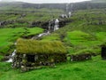 Faroe Islands. Saksun. Grass roofed buildings. Waterfall in the background.