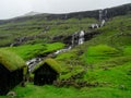 Faroe Islands. Saksun. Grass roofed buildings. Waterfall in the background.