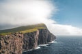 Faroe Islands Traelanipa the slaves rock cliff is seen rising over the ocean next to lake Sorvagsvatn. Clouds and blue Royalty Free Stock Photo