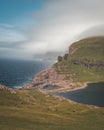 Faroe Islands Traelanipa the slaves rock cliff is seen rising over the ocean next to lake Sorvagsvatn. Clouds and blue Royalty Free Stock Photo