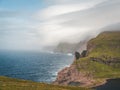 Faroe Islands Traelanipa the slaves rock cliff is seen rising over the ocean next to lake Sorvagsvatn. Clouds and blue Royalty Free Stock Photo