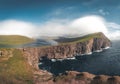 Faroe Islands Traelanipa the slaves rock cliff is seen rising over the ocean next to lake Sorvagsvatn. Clouds and blue Royalty Free Stock Photo