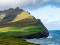 ViÃÂ°oy, ViÃÂ°areiÃÂ°i. Spectacular view on cliffs and green hills above the village. Blue sky with some while clouds