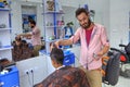 Iranian hairdresser cutting teenage boy`s hair inside barbershop
