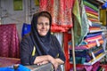 One mature Iranian woman in hijab sells textiles in bazaar.