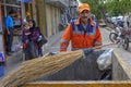 Garbage collector is pushing the cart on a city street.