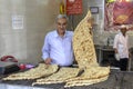 Shop at bakery, baker holding traditional Iranian flat bread lav
