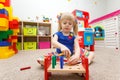 Fascinated child playing with wooden sticks in kindergarten